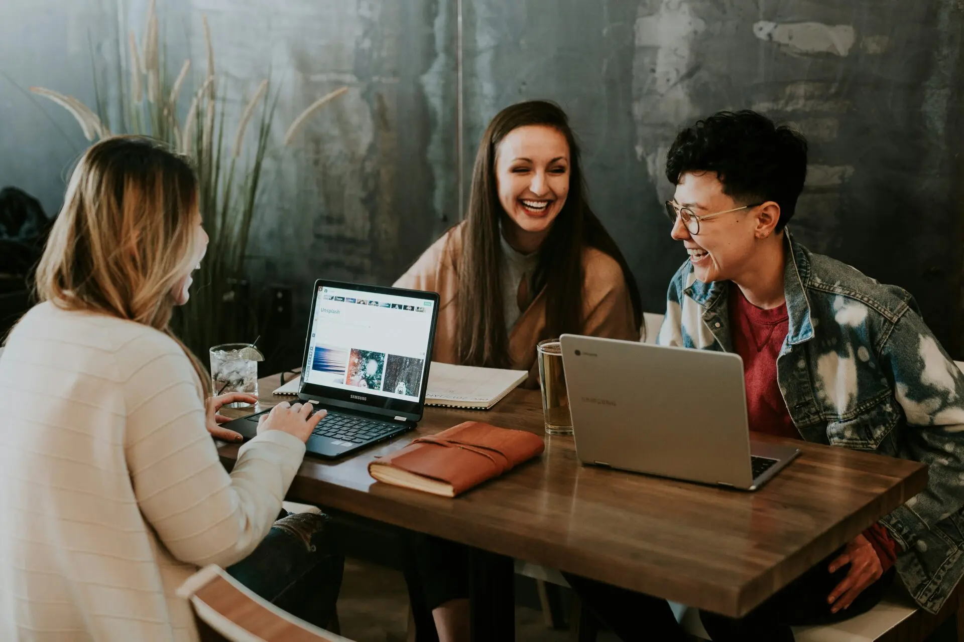 Drie mensen in overleg aan een tafel met laptops